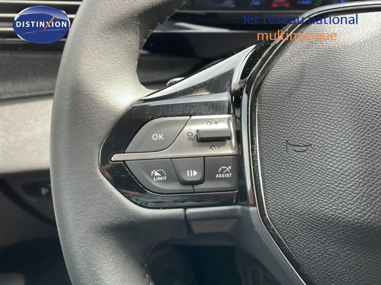Gros plan sur le volant noir du Peugeot 308 SW Hybrid 145ch, montrant les commandes de régulateur et d'assistance.