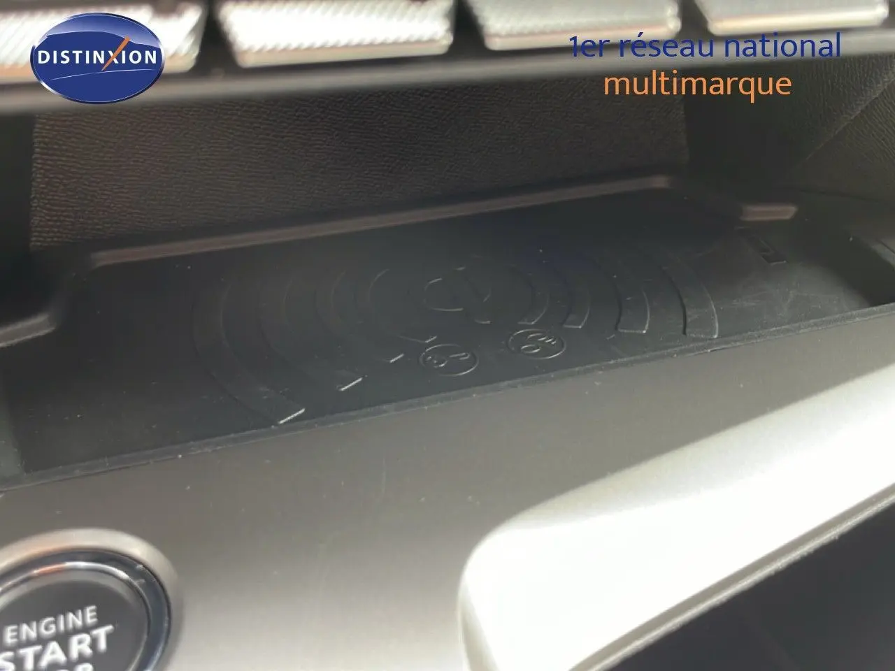 Gros plan sur la zone de recharge sans fil noire du tableau de bord de la Peugeot 308 SW Hybrid 2025.