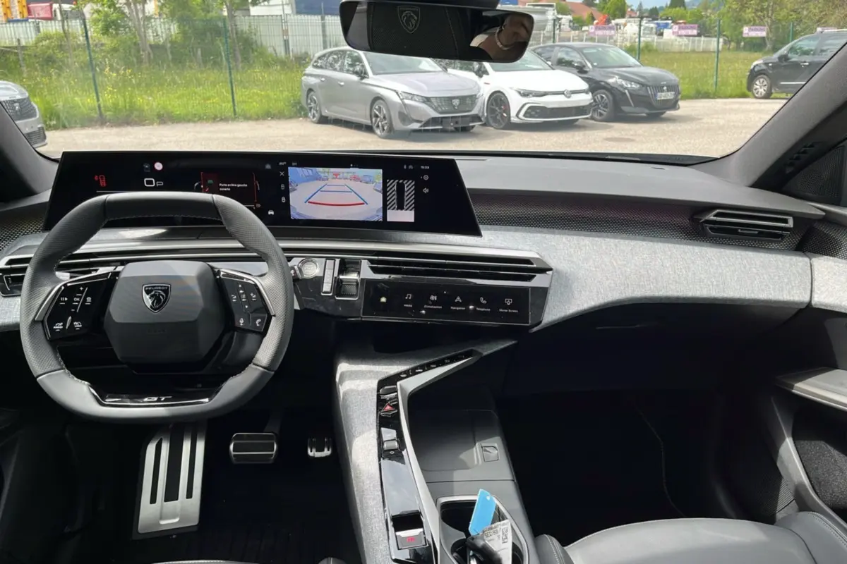 Vue intérieure du tableau de bord du Peugeot 3008 Hybrid 2025 avec volant multifonctions et écran central panoramique.