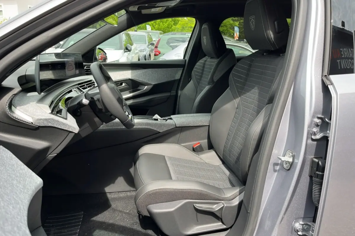 Vue intérieure côté conducteur du Peugeot 3008 Hybrid 2025, sièges noirs avec logo Peugeot brodé sur appuie-tête.