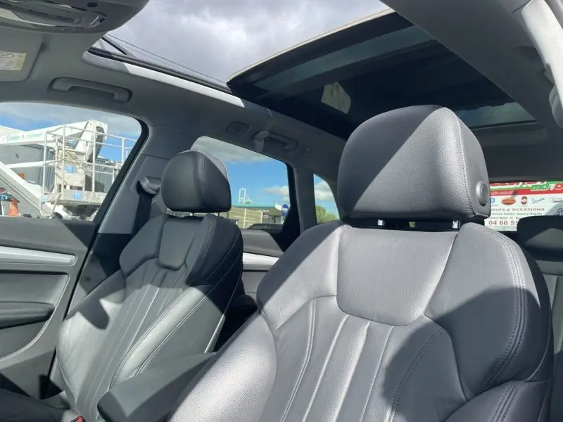 Intérieur de l'Audi Q5 2.0 TFSI 2017 avec sièges en cuir noir et toit ouvrant panoramique sous lumière naturelle.