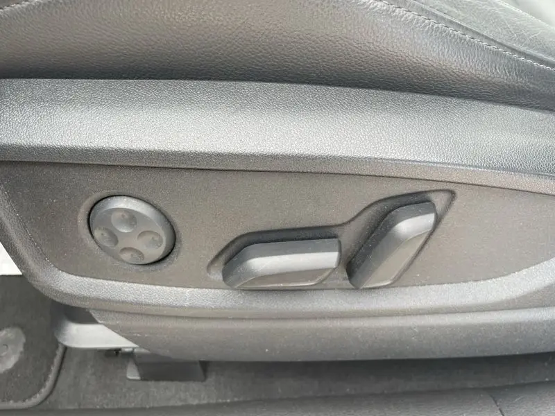 Réglages électriques des sièges en gros plan sur le côté gauche de l'intérieur noir d'un Audi Q5 2017.