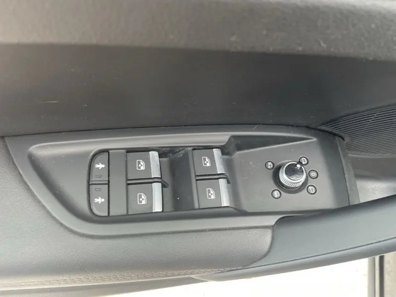 Gros plan sur les commandes des vitres et rétroviseurs côté conducteur d'un Audi Q5 2017 noir métal.