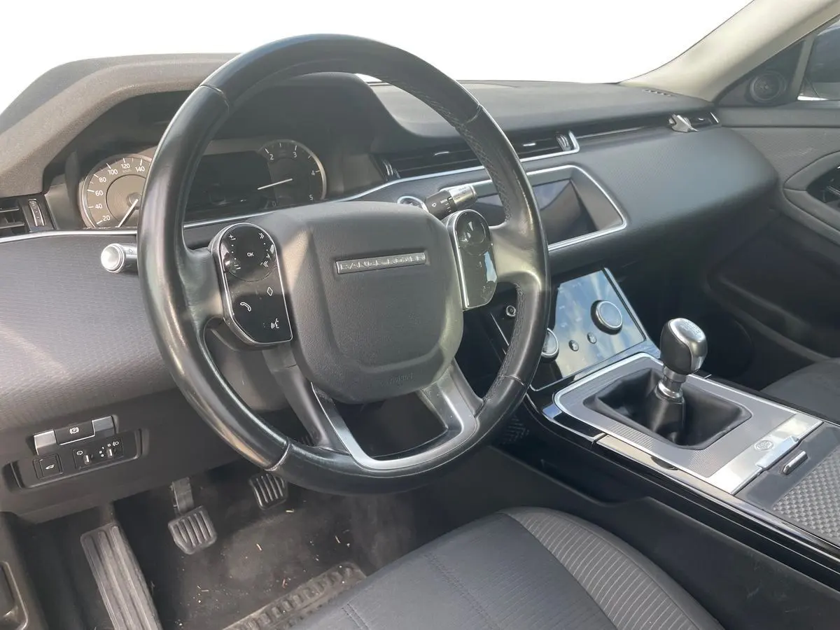 Intérieur du Range Rover Evoque 2020 blanc, vue côté conducteur sur le volant et la boîte manuelle noire.