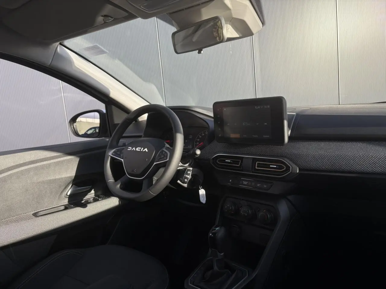 Intérieur côté conducteur de la Dacia Sandero Stepway blanc glacier, volant avec logo et écran tactile central visible