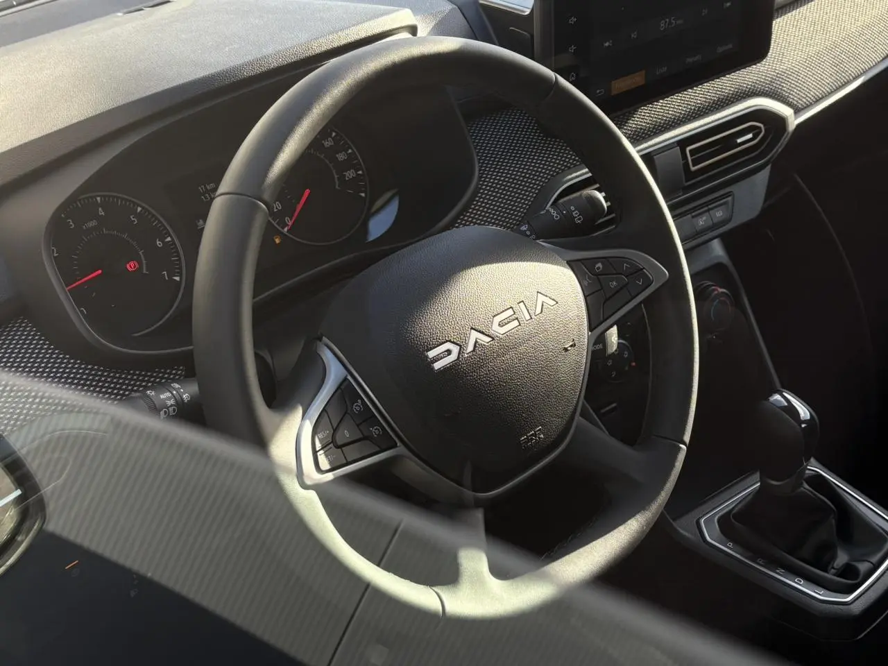 Vue rapprochée du volant Dacia et de la console centrale avec levier de vitesse de la Sandero Stepway 2024.