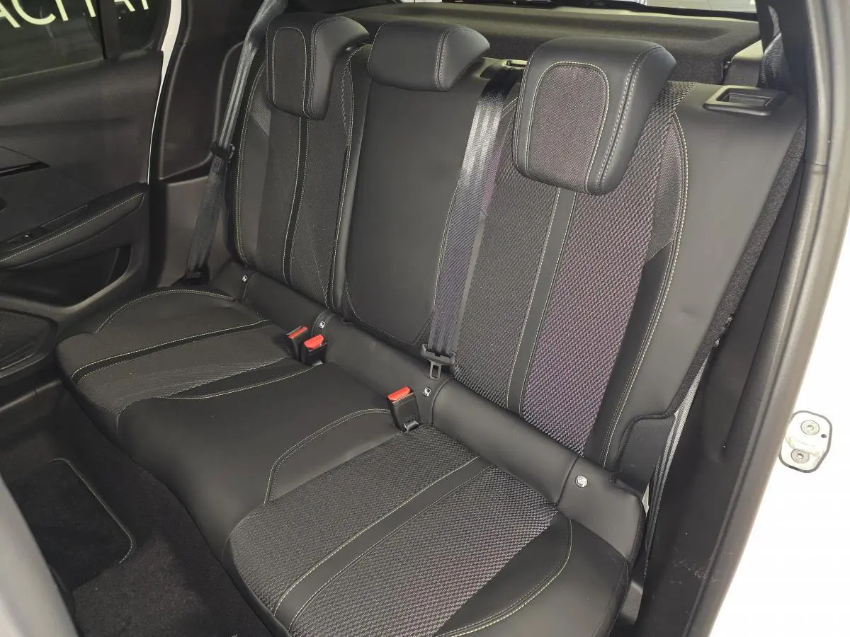 Vue intérieure côté droit sur la banquette arrière noire avec surpiqûres vertes de la Peugeot 208 blanche 2025.