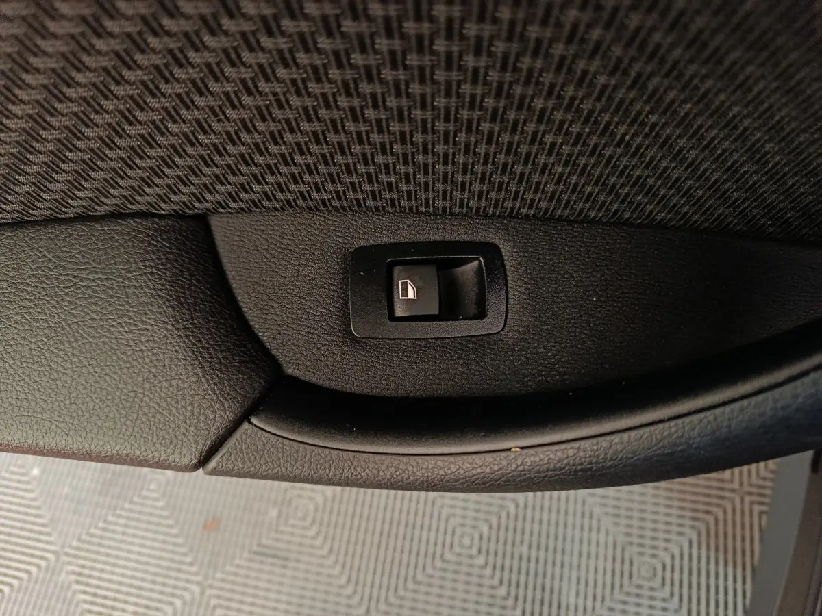 Bouton de commande de lève-vitre sur panneau de porte intérieur noir d'une BMW X1 sDrive18i Lounge 2021.