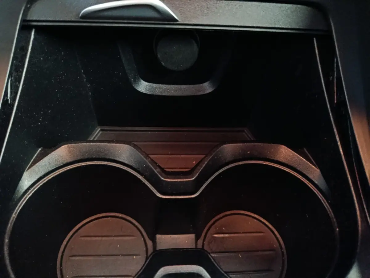 Gros plan sur les porte-gobelets noirs au centre de la console intérieure du BMW X1 sDrive18i Lounge gris foncé.