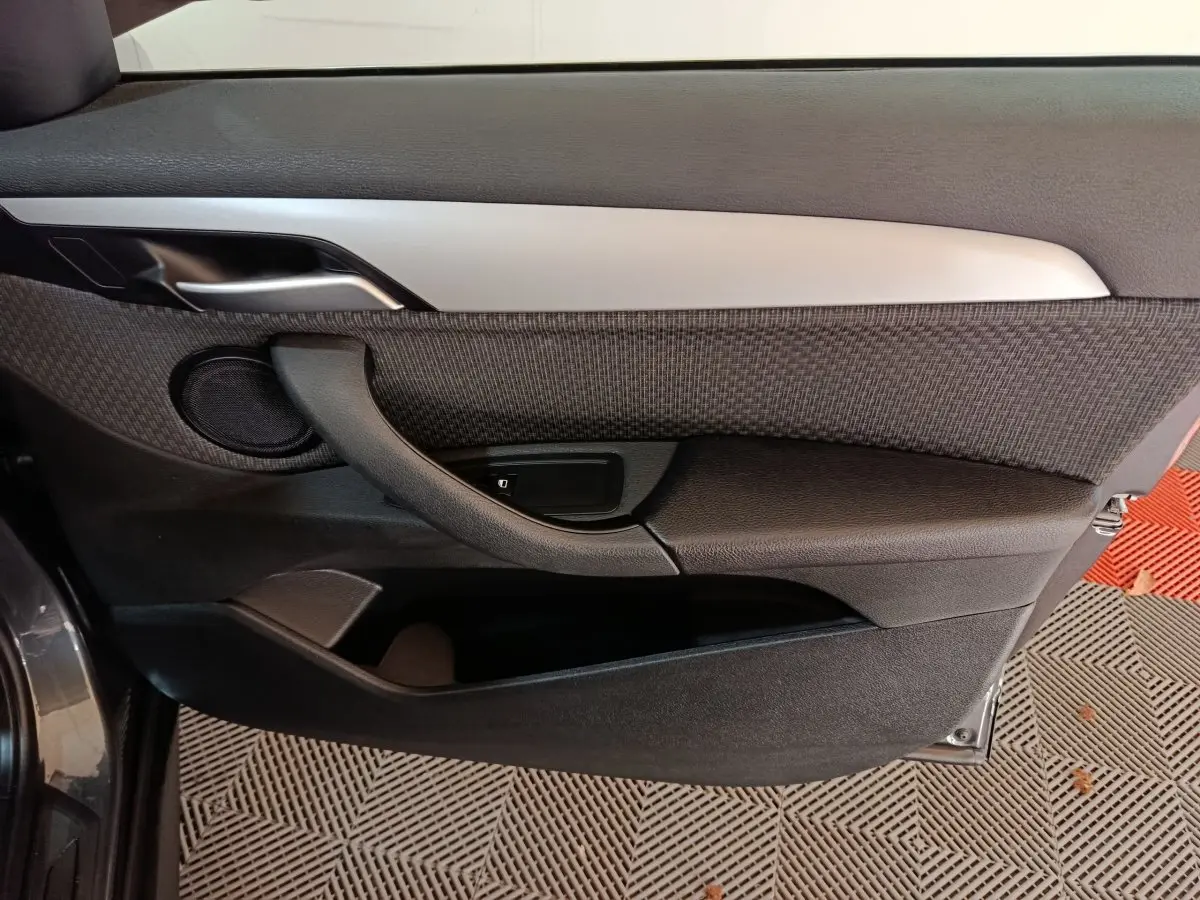 Vue rapprochée de la porte avant gauche du BMW X1 sDrive18i Lounge 2021 en gris foncé, avec garniture tissu et plastique noir.