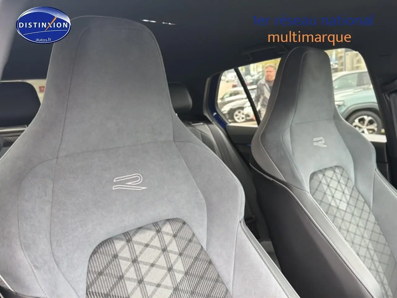 Gros plan sur les sièges avant sport gris avec logo R de la Volkswagen Golf 2024, intérieur visible côté droit.