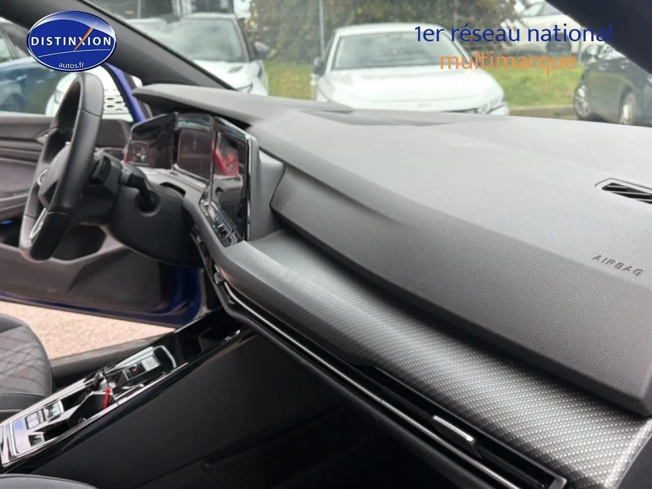 Vue intérieure côté passager de la Volkswagen Golf 2024 bleu, avec tableau de bord moderne et volant cuir visible.