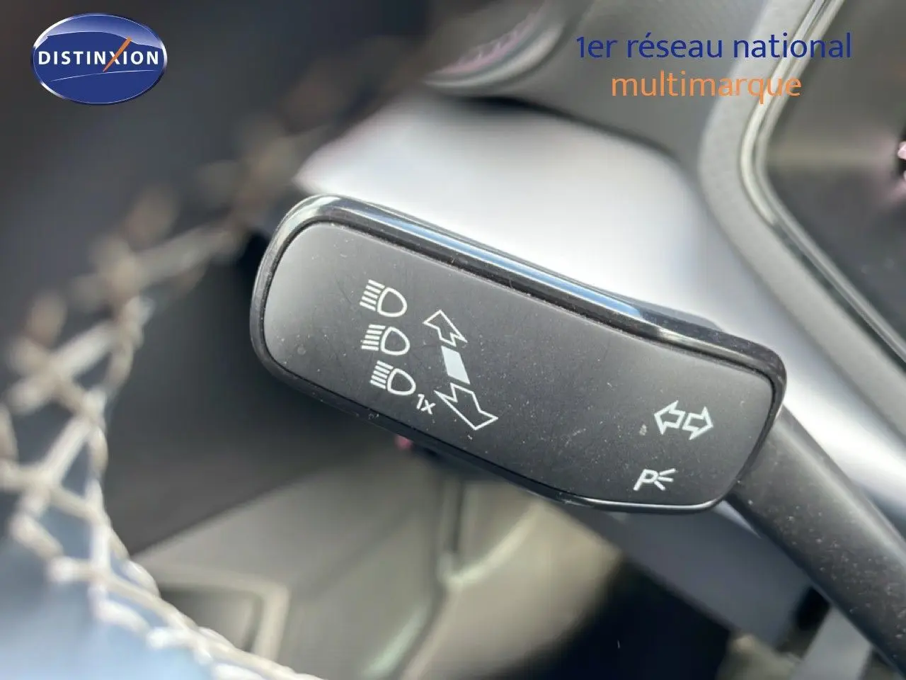 Gros plan sur la manette de clignotants et feux d'une SEAT Ibiza bleu Fjord, intérieur noir visible en arrière-plan.