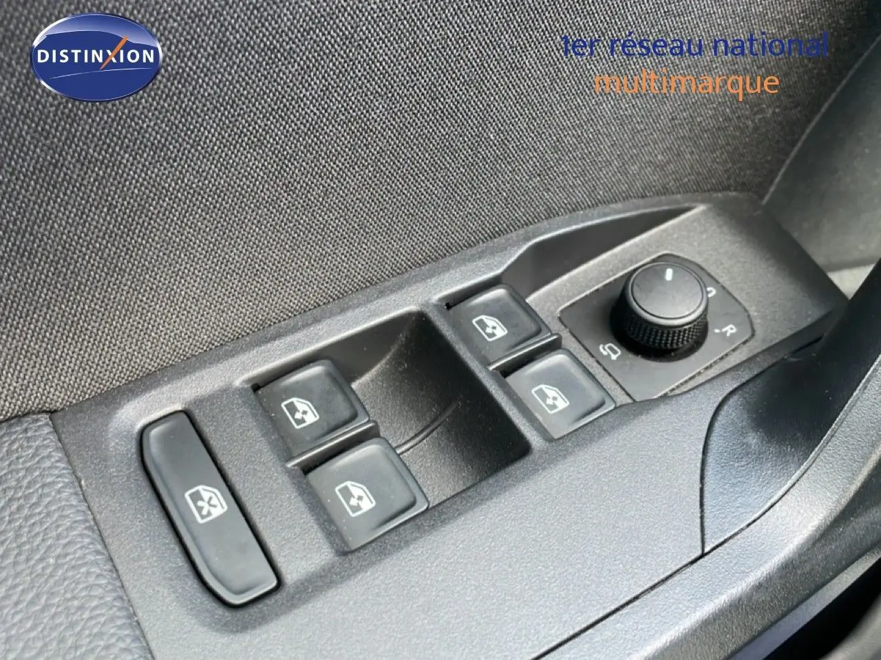 Gros plan sur les commandes des vitres et rétroviseurs côté conducteur d'une SEAT Ibiza bleu Fjord 2025.