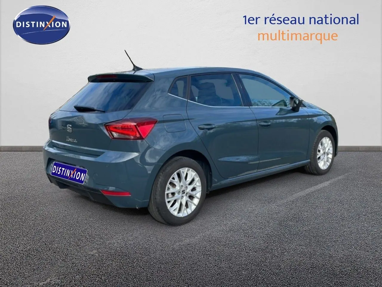 Vue 3/4 arrière droite d'une SEAT Ibiza bleu fjord avec jantes alliage et vitres teintées sur parking.