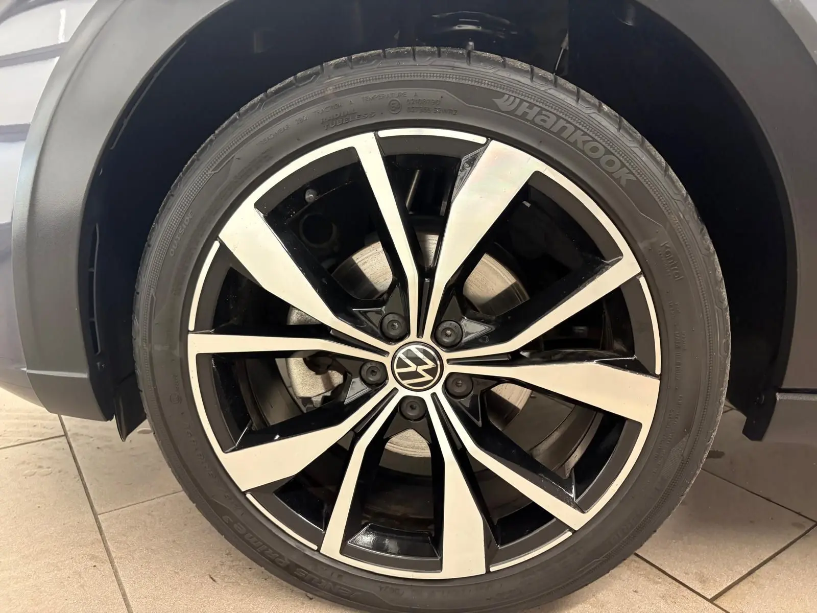 Gros plan sur la jante alliage noir et argentée 18 pouces du Volkswagen Taigo gris cendré, avec logo VW central.