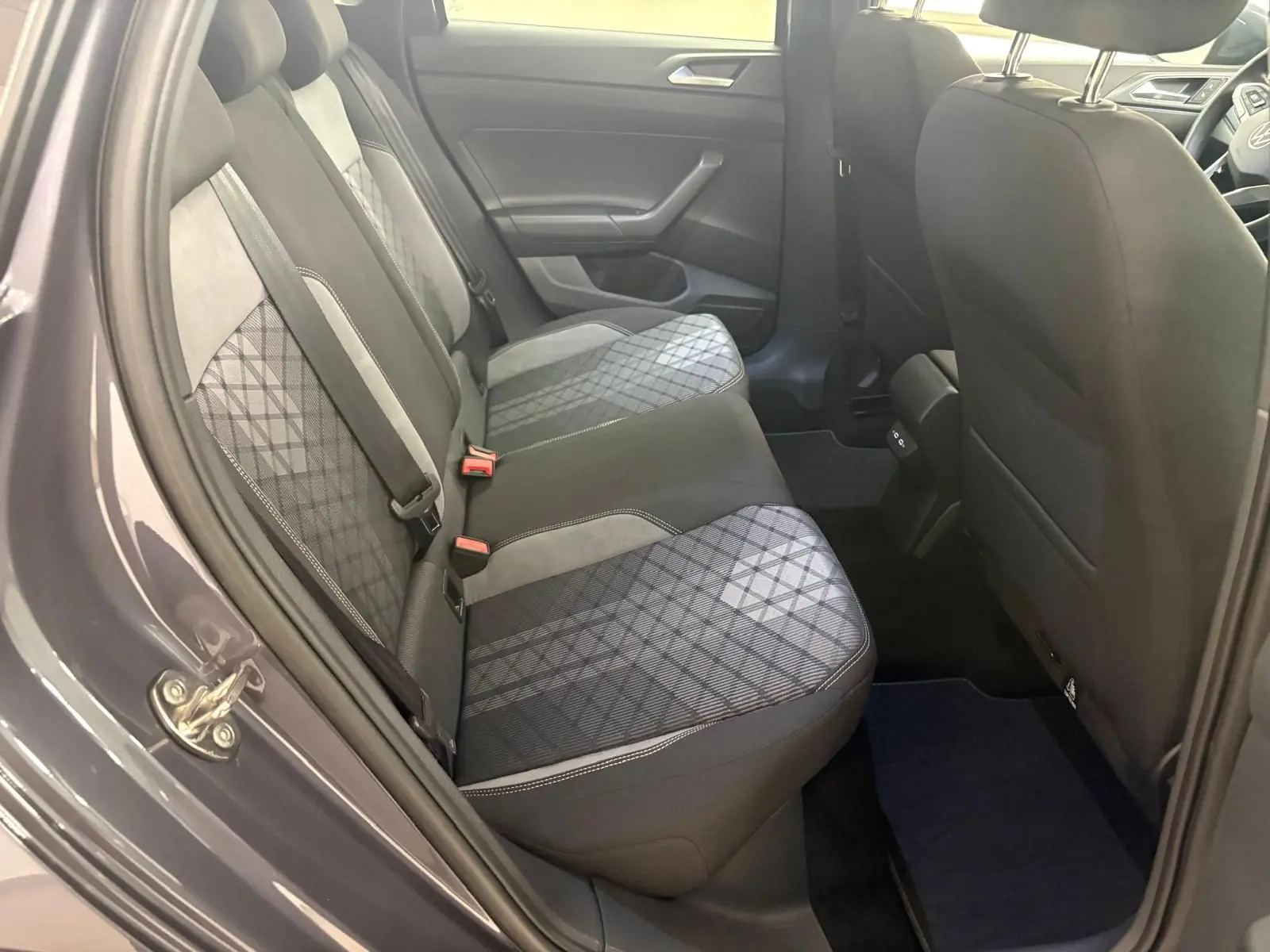Vue côté gauche sur l'arrière du Volkswagen Taigo gris cendré, montrant les sièges arrière en tissu à motif géométrique.