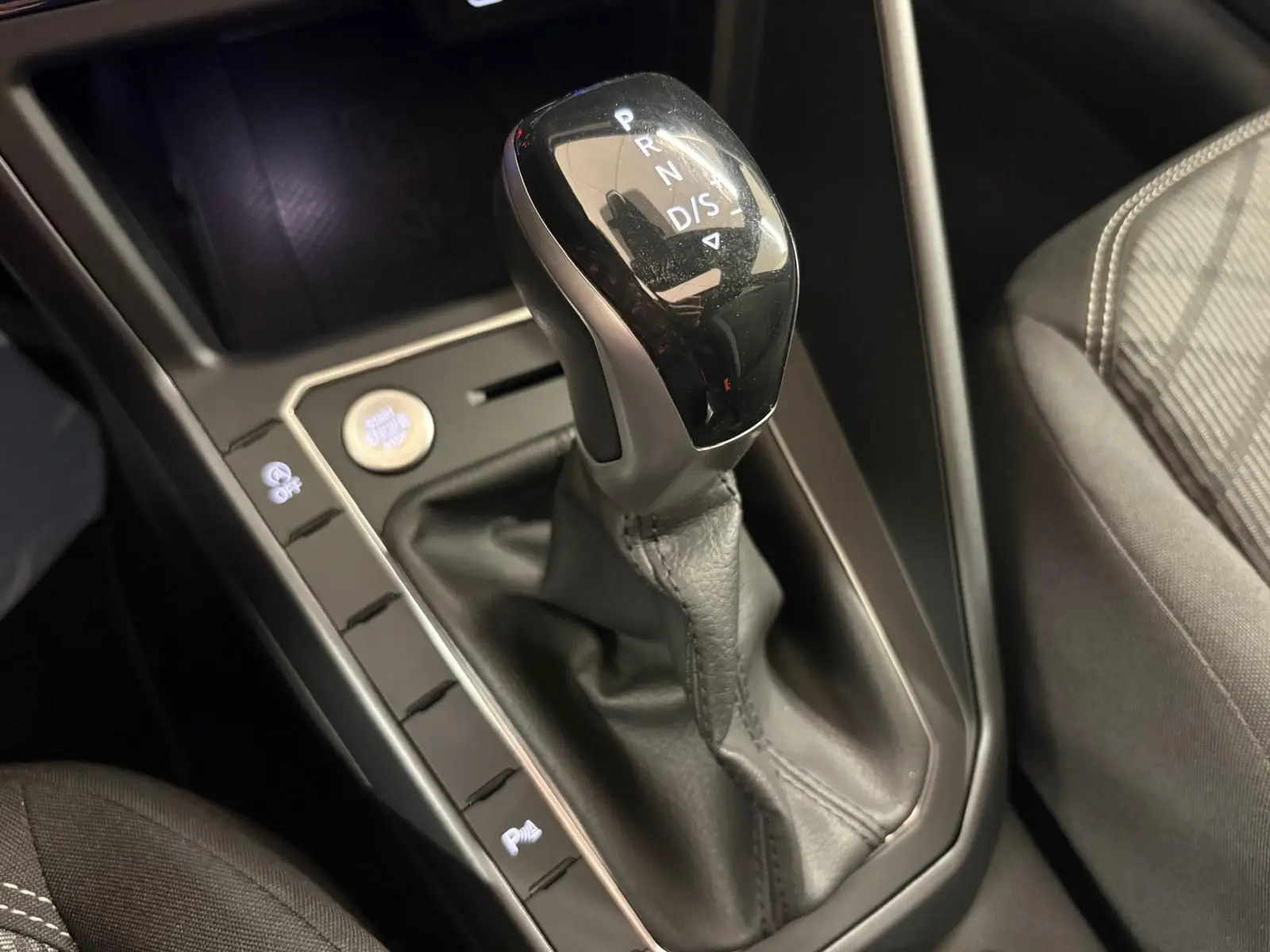 Gros plan sur la commande de boîte automatique noire et grise dans l'habitacle du Volkswagen Taigo gris cendre.