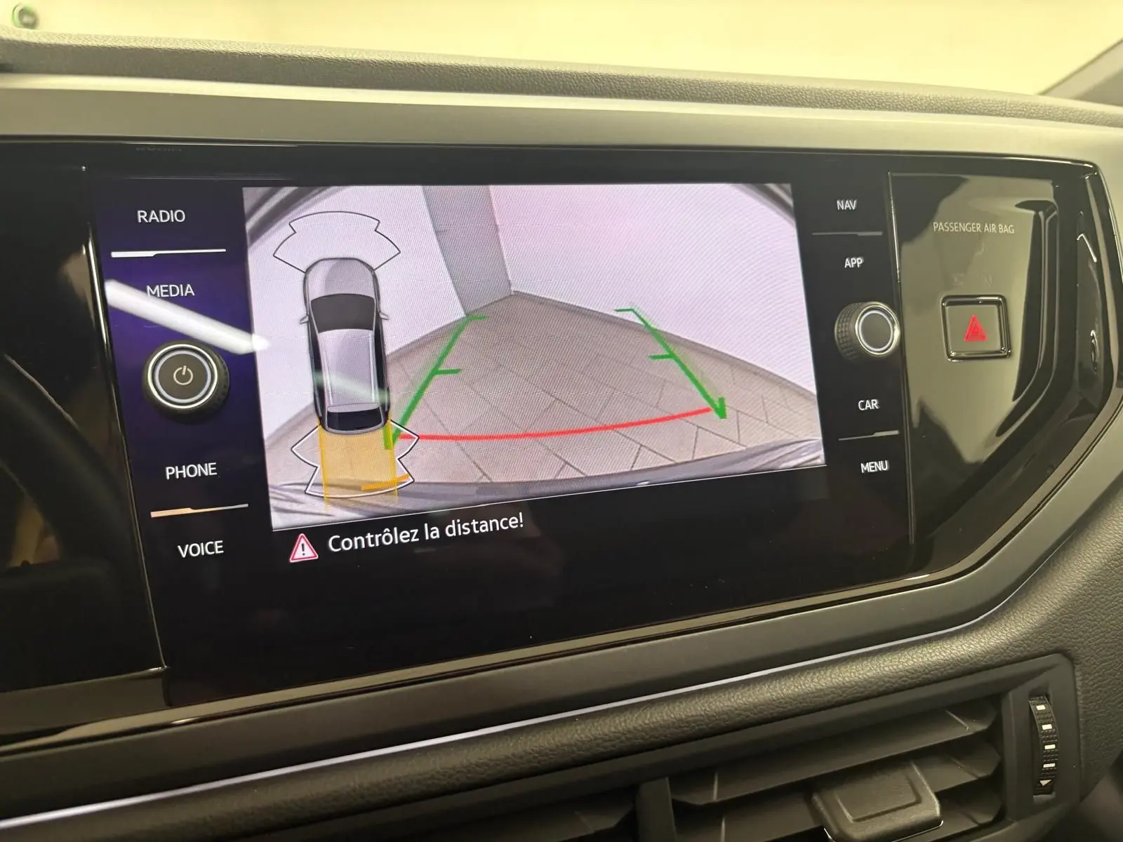 Vue de l'écran central affichant la caméra de recul du Volkswagen Taigo gris cendré avec alertes de distance.
