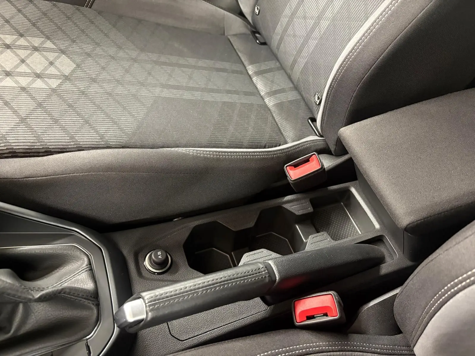 Vue rapprochée de la console centrale et des sièges avant gris foncé du Volkswagen Taigo 2024, version R-Line.