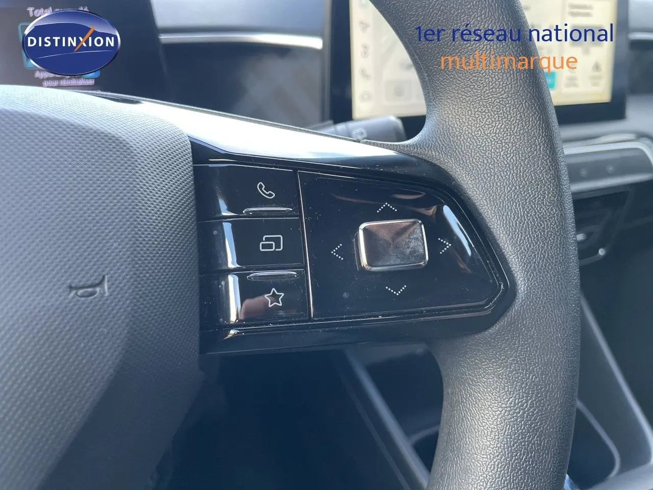 Gros plan sur les commandes gauche du volant noir texturé du MG3 2024, avec boutons multifonctions et écran tactile en arrière-plan.