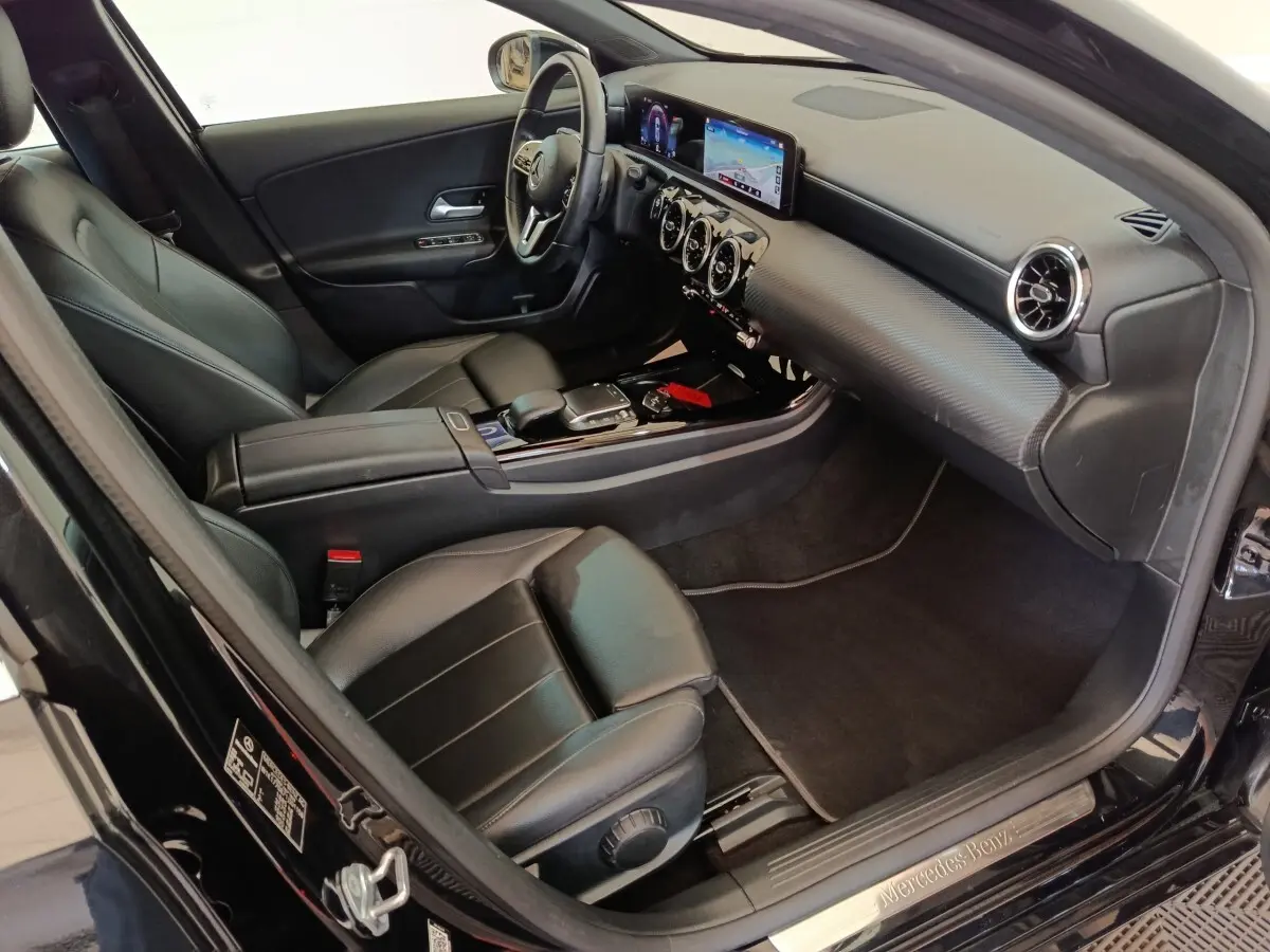Vue intérieure côté conducteur de la Mercedes Classe A 200 Business Line 2021 noire, avec tableau de bord numérique et sièges cuir noirs.