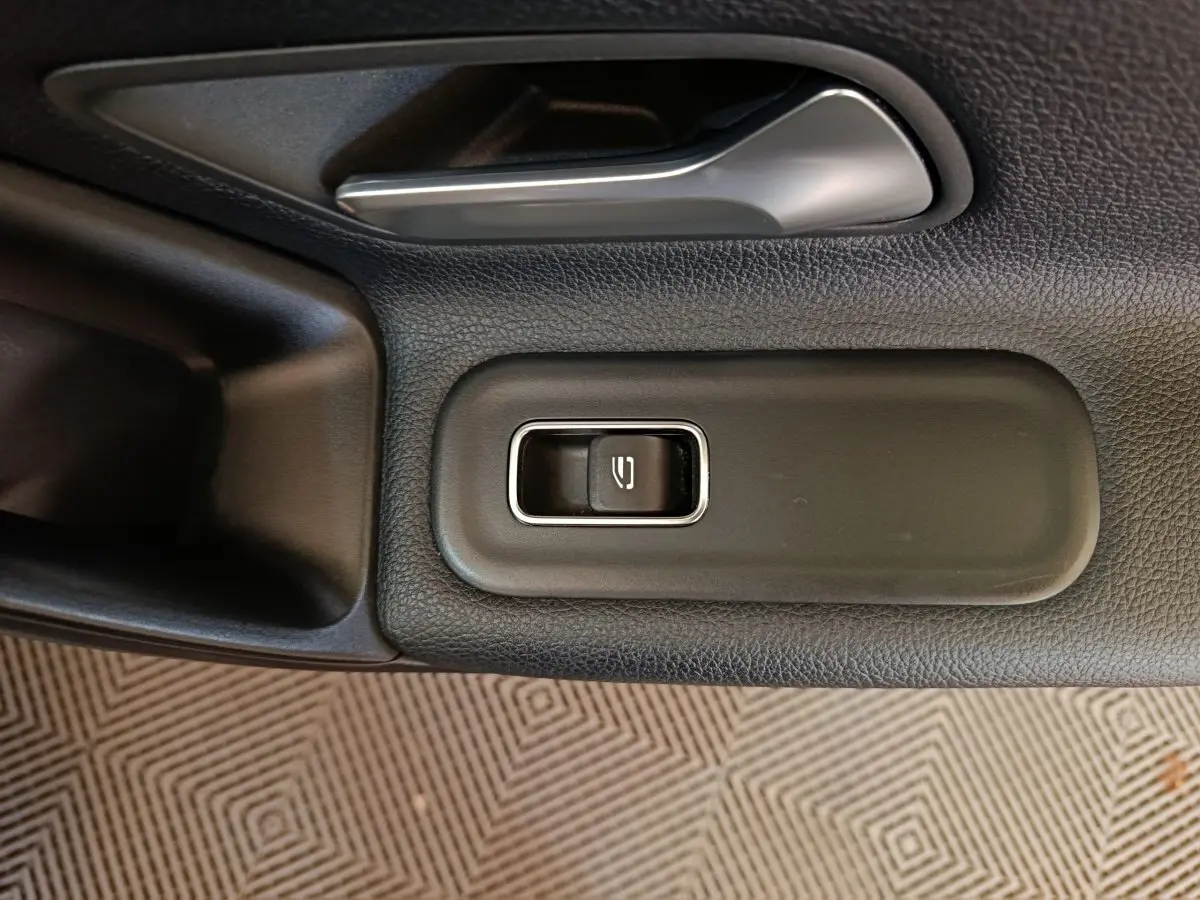 Gros plan sur la commande de verrouillage de porte côté gauche dans l'habitacle noir d'une Mercedes Classe A 200 Business Line.