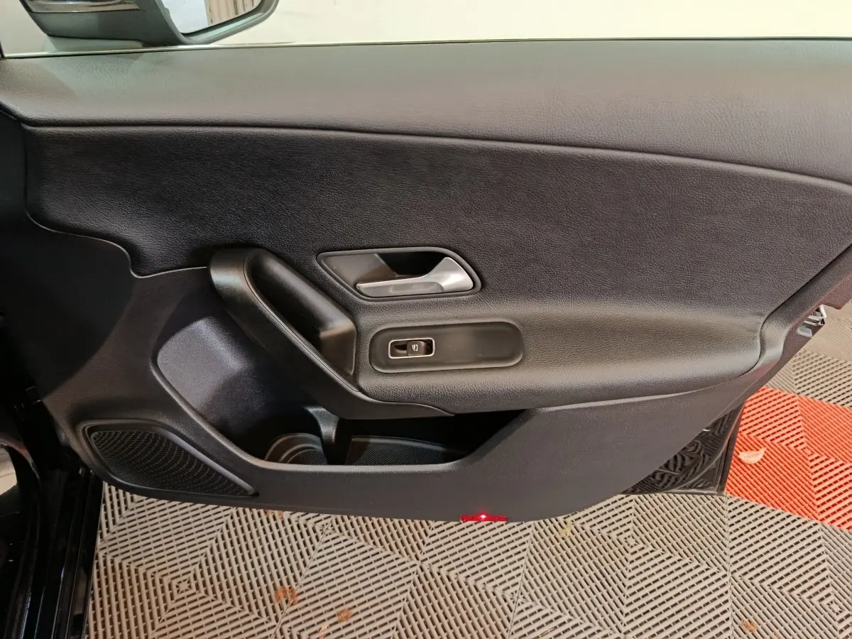 Vue intérieure côté gauche de la porte avant noire d'une Mercedes Classe A 200 Business Line avec poignée et commande de vitre.
