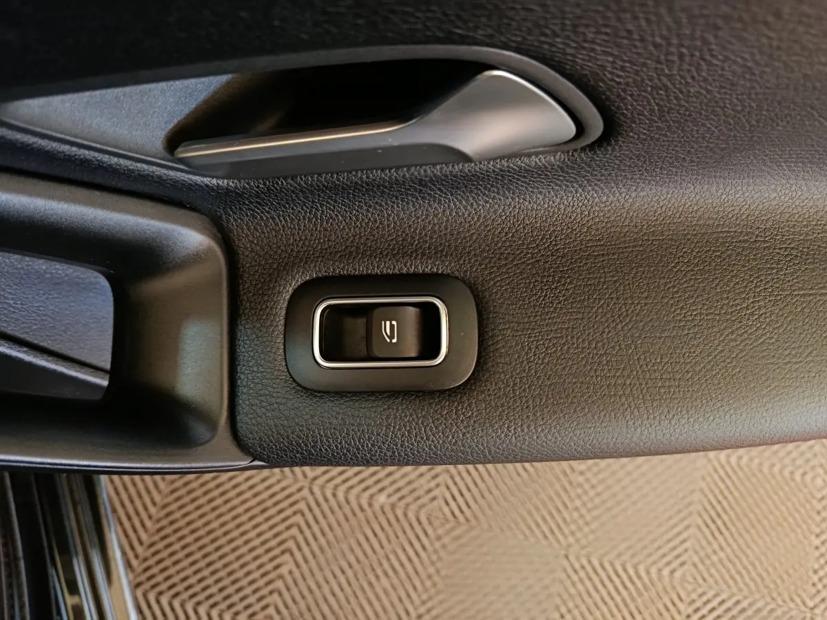 Gros plan sur le bouton d'ouverture de coffre intégré à la garniture intérieure noire d'une Mercedes Classe A 200 Business Line.