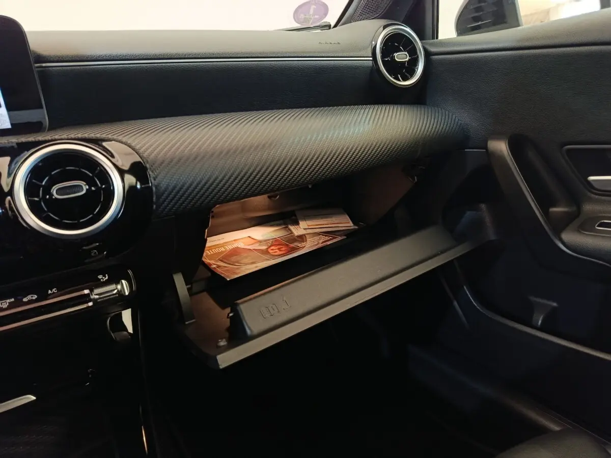 Intérieur noir de la Mercedes Classe A 200 Business Line 2021, vue côté passager avec boîte à gants ouverte.