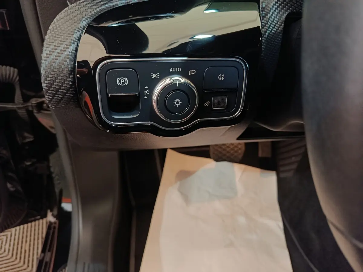 Gros plan sur le panneau de commande des feux et frein à main électrique, intérieur noir de la Mercedes Classe A 200.