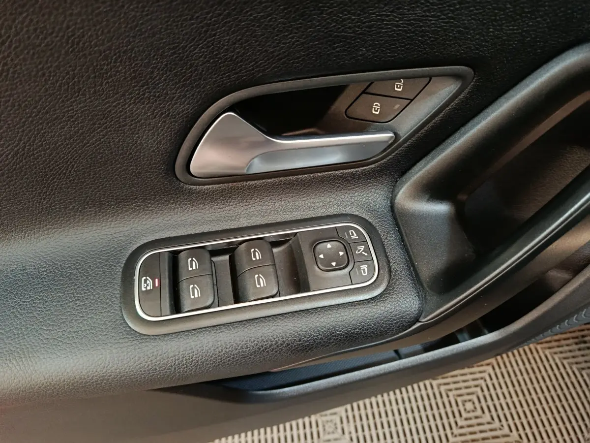 Gros plan sur la porte côté gauche noire de la Mercedes Classe A 200 Business Line avec commandes de vitres et rétroviseurs.