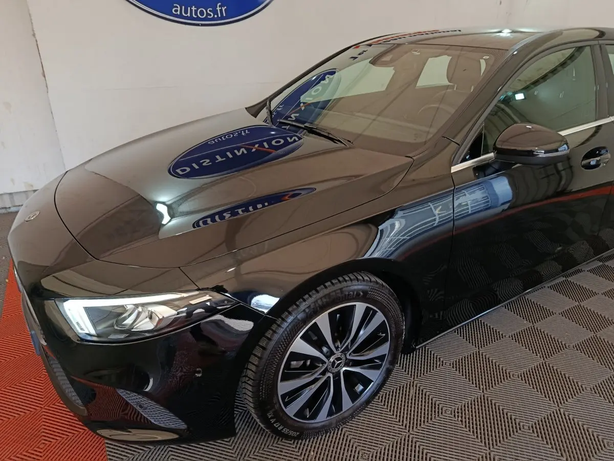 Vue 3/4 avant droit d'une Mercedes Classe A 200 Business Line noire avec jantes alliage et phares LED allumés.