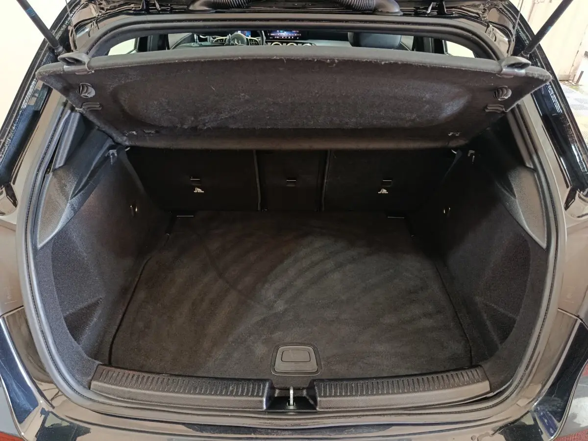 Coffre ouvert vu de l'arrière d'une Mercedes Classe A 200 Business Line noire, espace de chargement vide et propre.