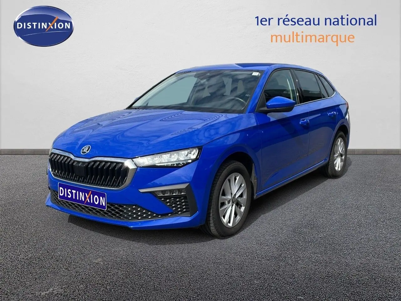 SKODA SCALA bleu racing metal en 3/4 avant droit, mettant en valeur sa calandre noire et ses phares LED fins.