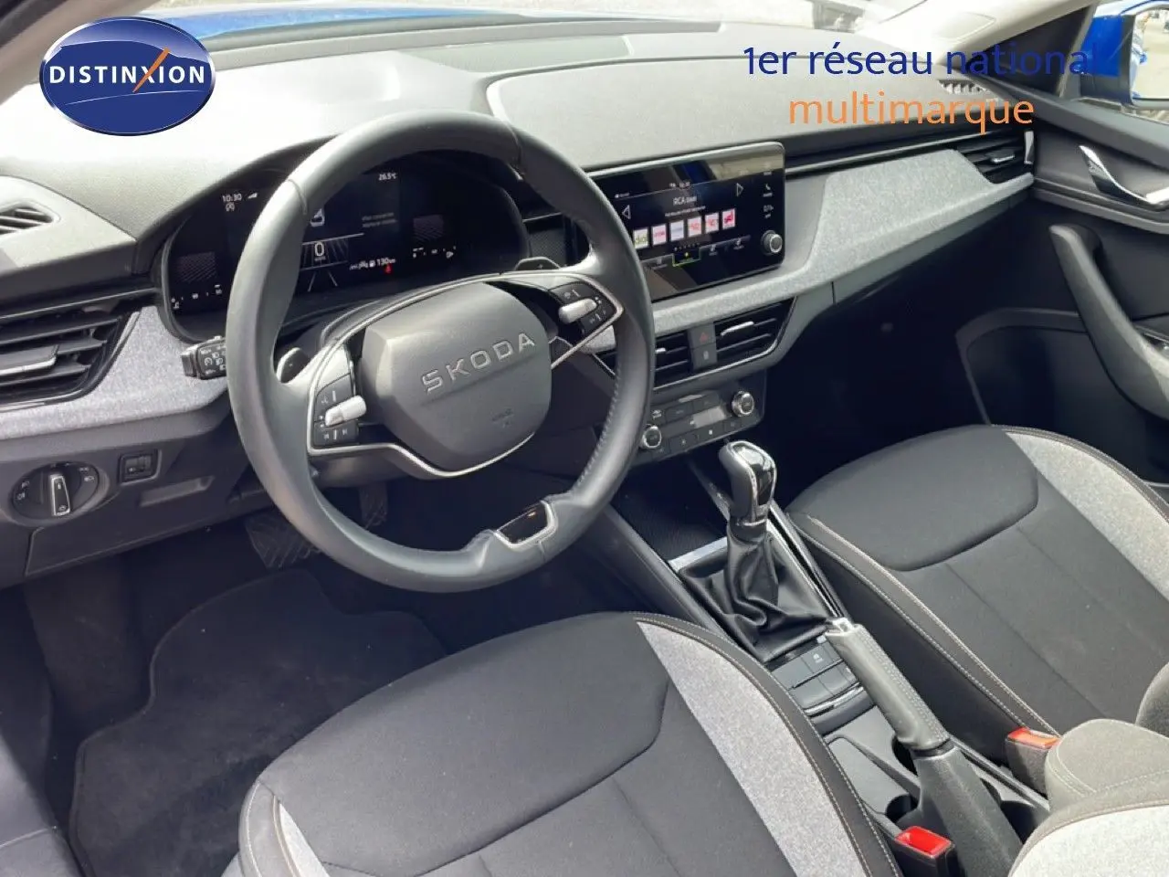 Vue intérieure côté conducteur de la Skoda Scala 2025, volant multifonction et sellerie tissu gris et noir.