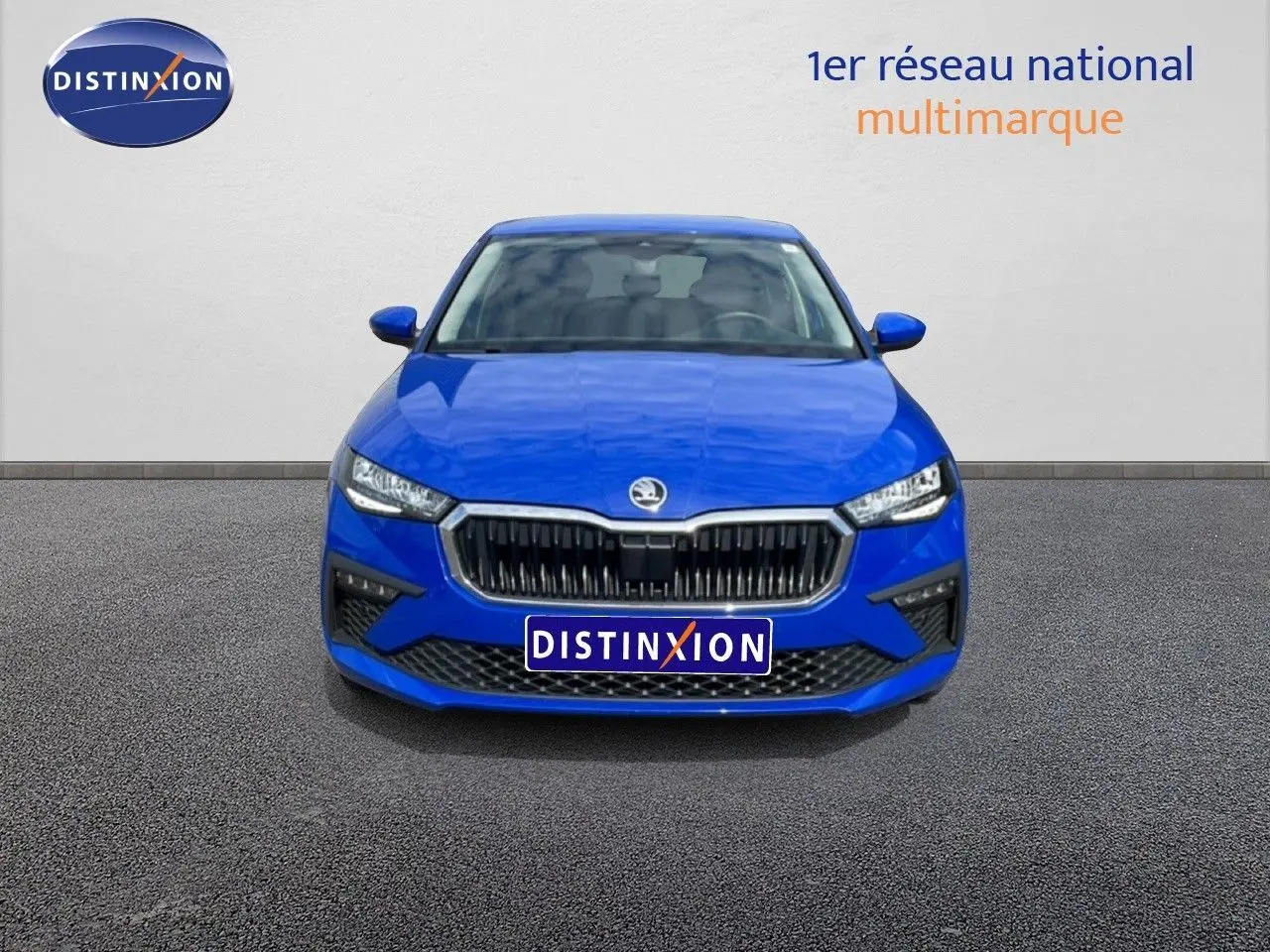 Vue frontale d'une Skoda Scala 2025 bleu racing metal avec calandre noire et phares LED allumés.