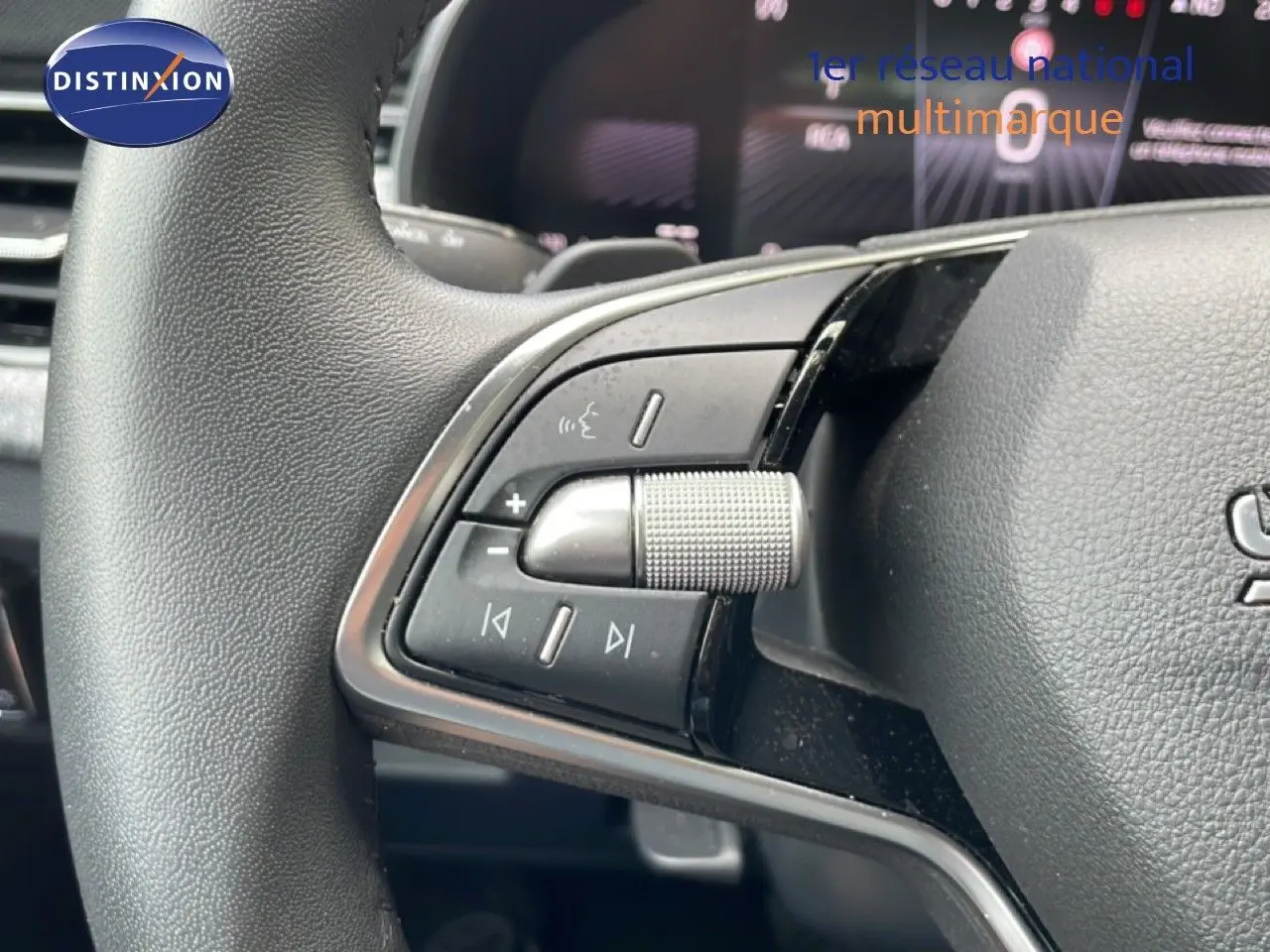 Gros plan sur les commandes multimédia au volant d’une Skoda Scala 2025, finition tissu noir.