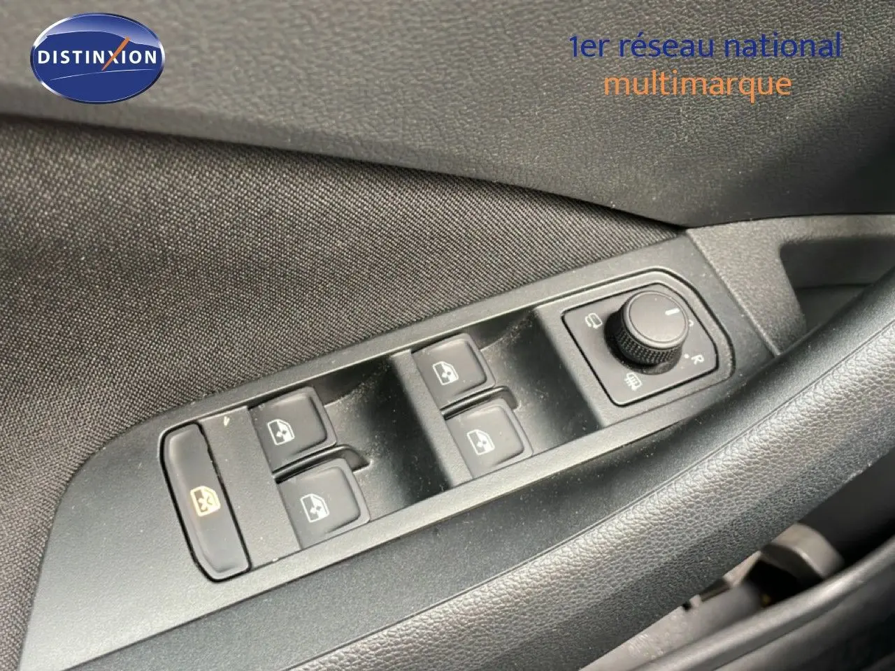 Gros plan sur les commandes de lève-vitres et réglage des rétroviseurs côté conducteur d’une Skoda Scala bleu Racing Metal.