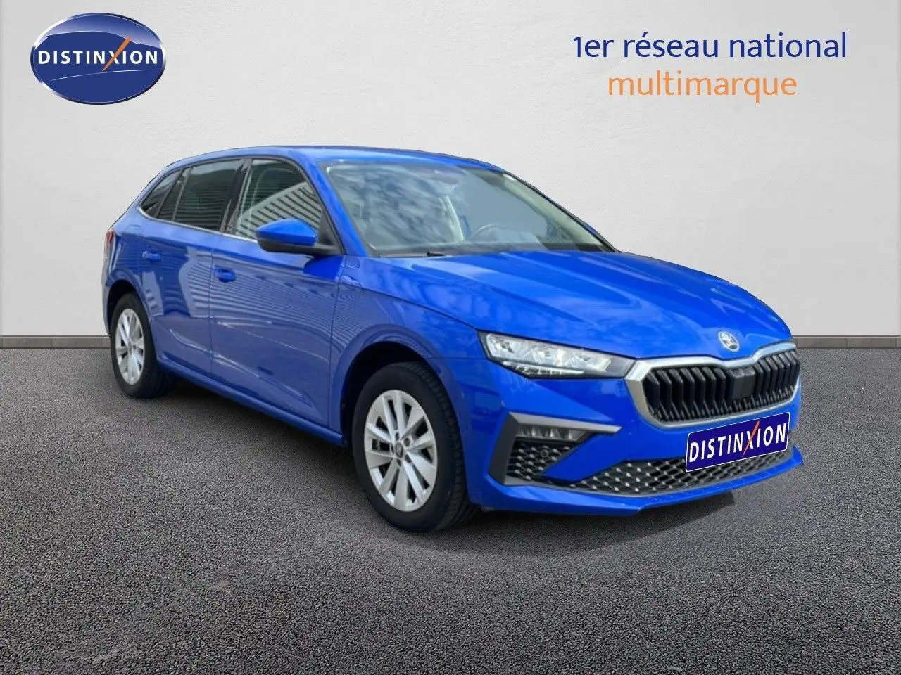 Skoda Scala 1.0 TSI bleu racing metal en 3/4 avant droit, avec calandre noire et jantes argentées.