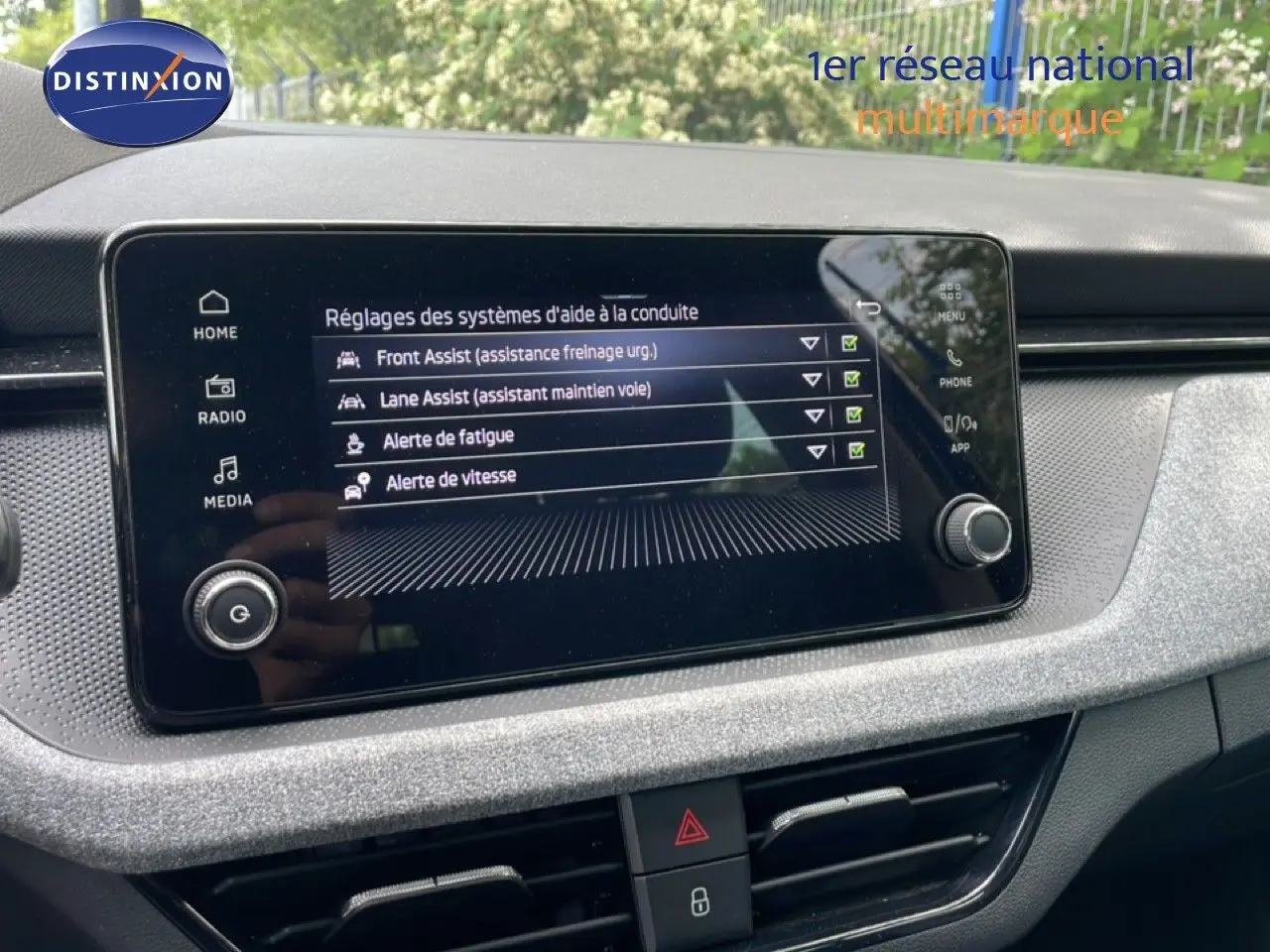 Écran tactile central affichant les réglages d’aides à la conduite dans l’habitacle gris noir d’une Skoda Scala 2025.