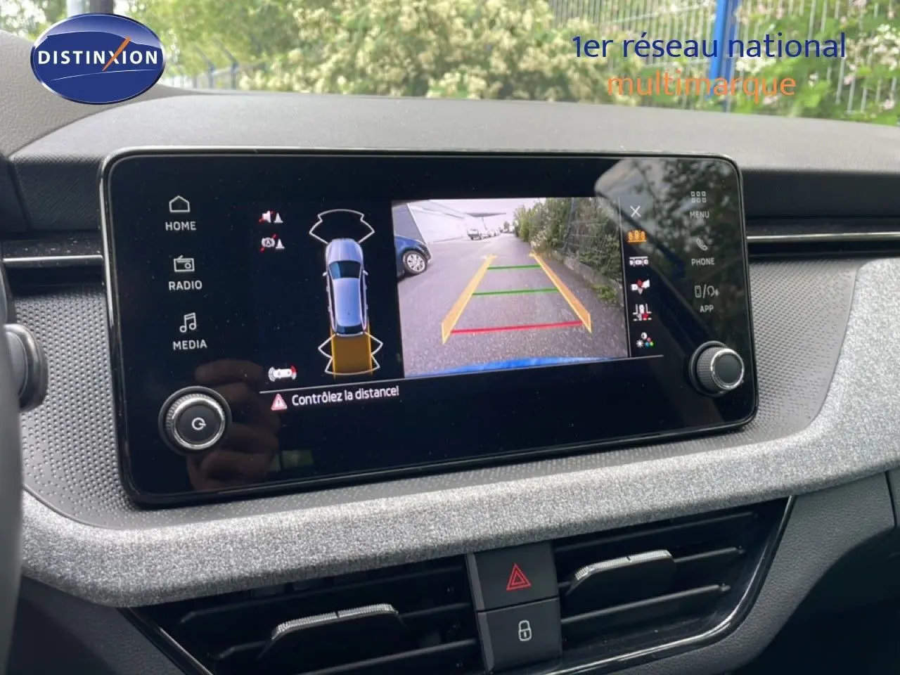 Écran central de la Skoda Scala bleu racing montrant la caméra de recul avec guidage de trajectoire.