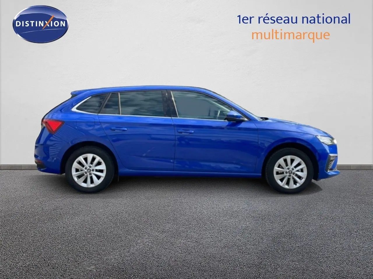 Profil droit d'une Skoda Scala 2025 bleu racing metal avec jantes alliage et vitres teintées, sur fond neutre intérieur.