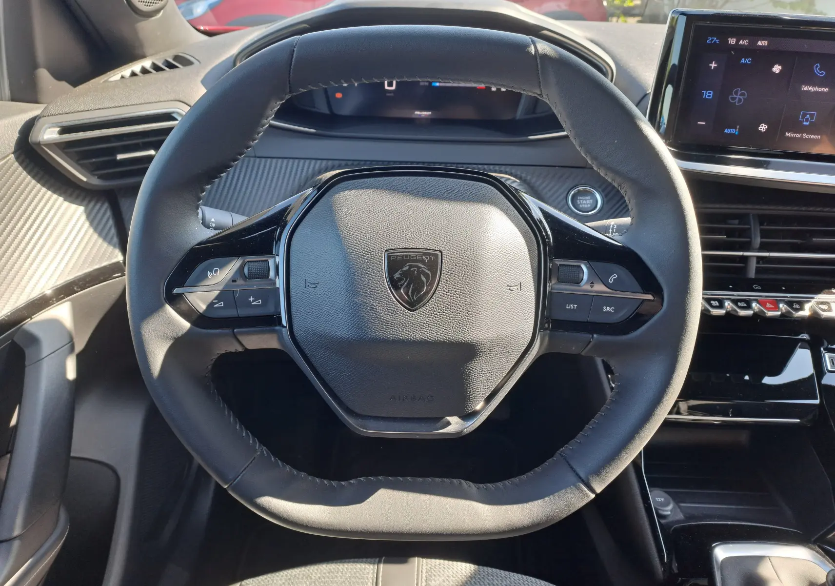 Vue rapprochée du volant cuir noir du Peugeot 2008 1.2 PureTech 100 Allure 2023 avec tableau de bord numérique.