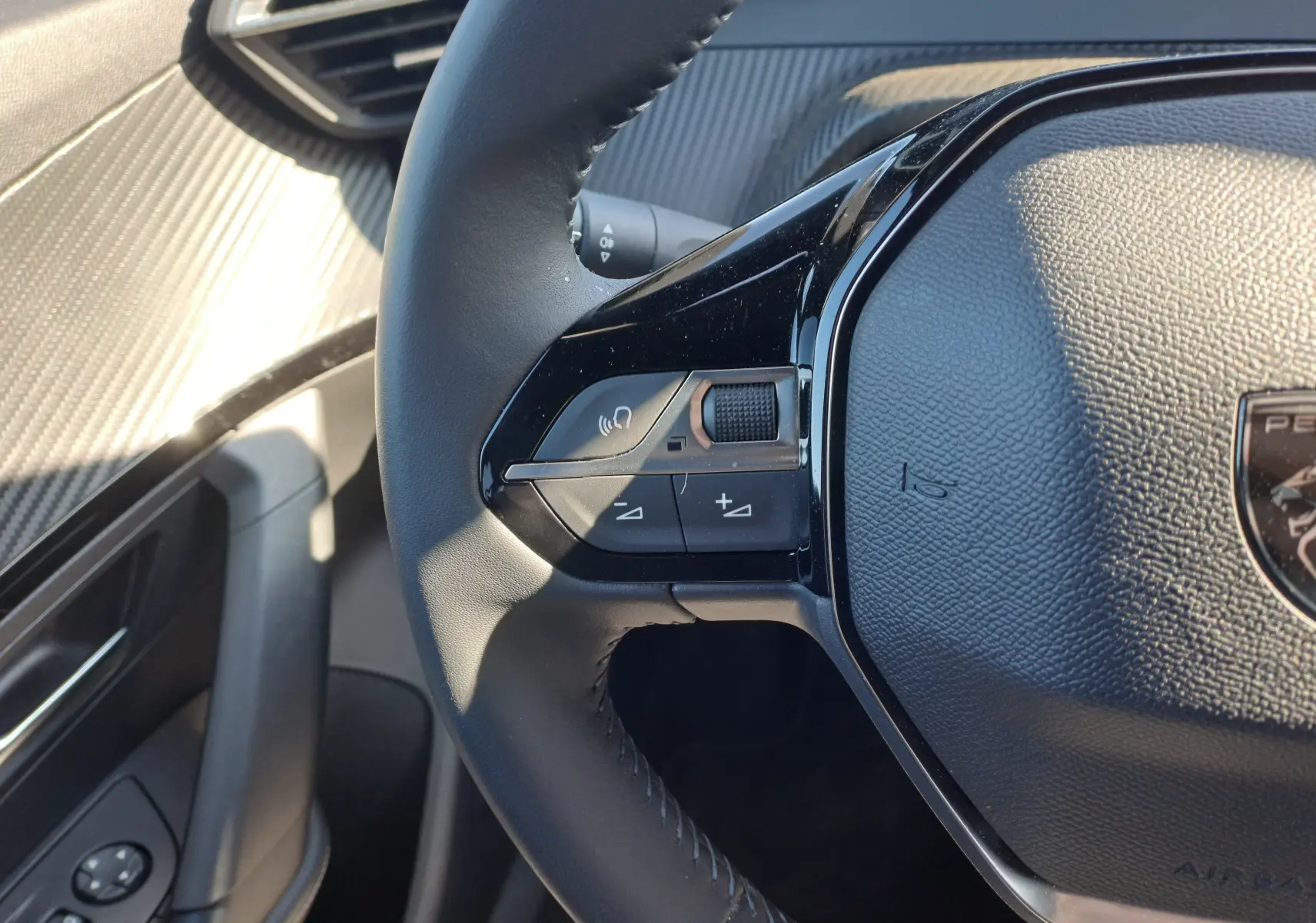 Gros plan sur la partie gauche du volant noir du Peugeot 2008 2023, montrant les commandes de volume et de voix.