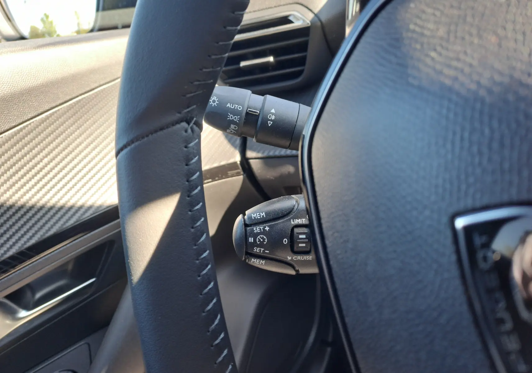 Gros plan sur la commande de régulateur de vitesse et les commandes d'éclairage du côté gauche du volant d'un Peugeot 2008.