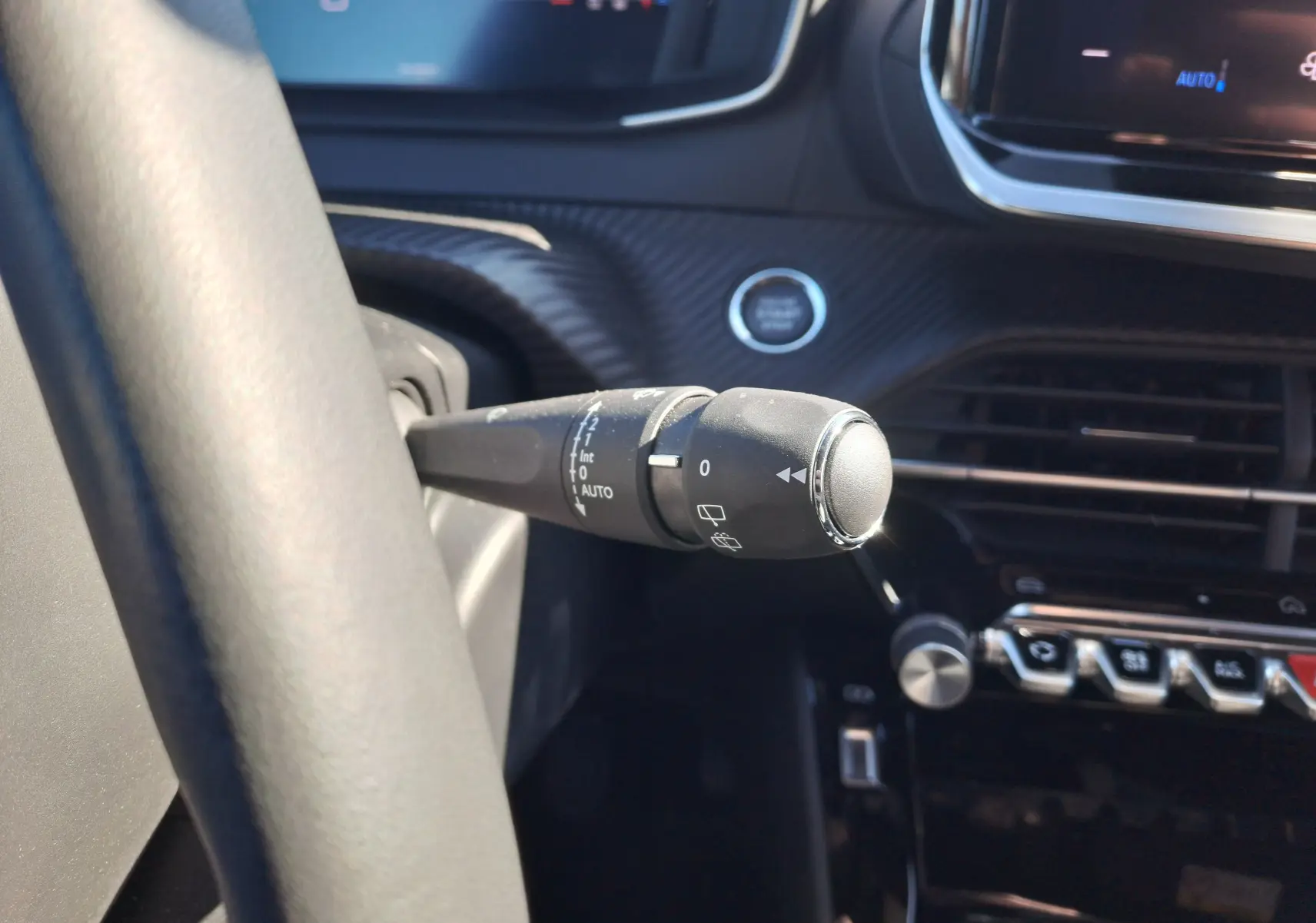 Gros plan sur la commande d'essuie-glace à gauche du volant dans l'habitacle noir du Peugeot 2008 rouge Elixir 2023.