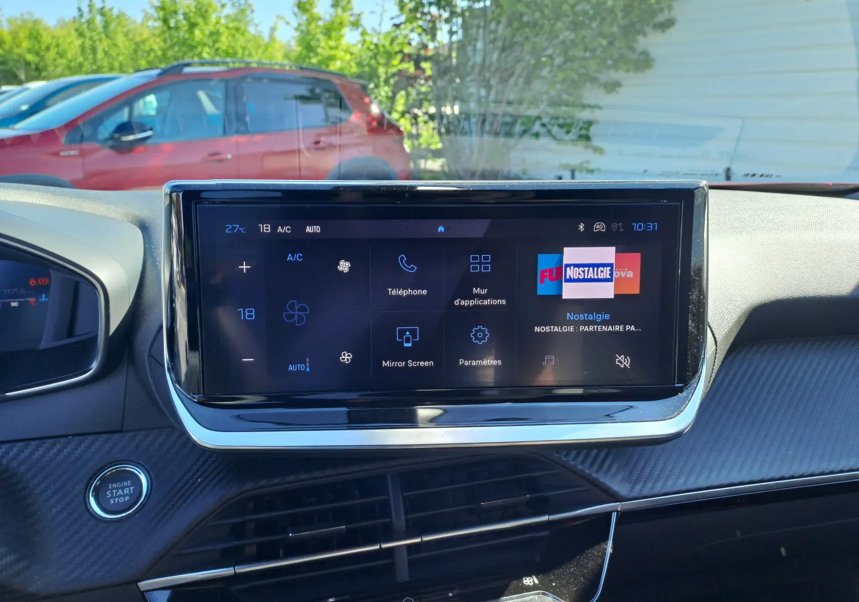 Vue intérieure du tableau de bord du Peugeot 2008 Rouge Elixir 2023 avec écran tactile central et bouton start/stop visible.