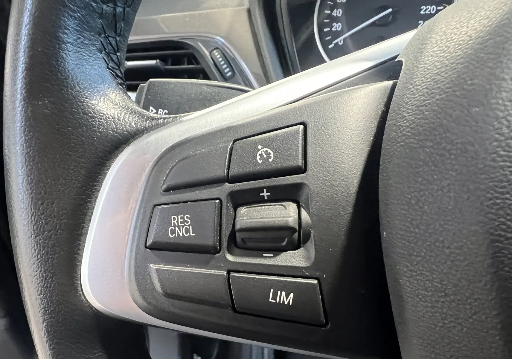 Gros plan sur les commandes de régulateur de vitesse au volant noir du BMW X1 F48 Saphirschwarz de 2017.