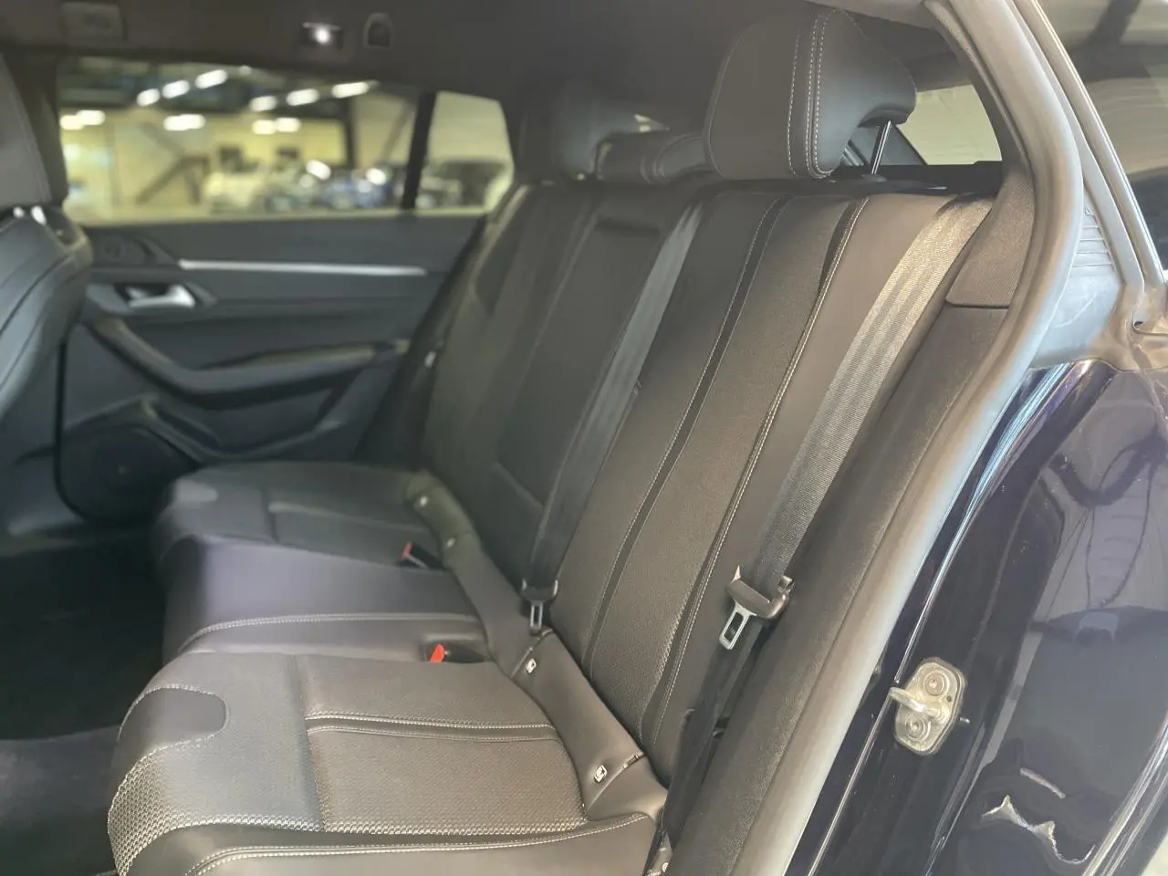Vue côté droit des sièges arrière en cuir noir de la Peugeot 508 SW bleu foncé, avec ceinture de sécurité visible.